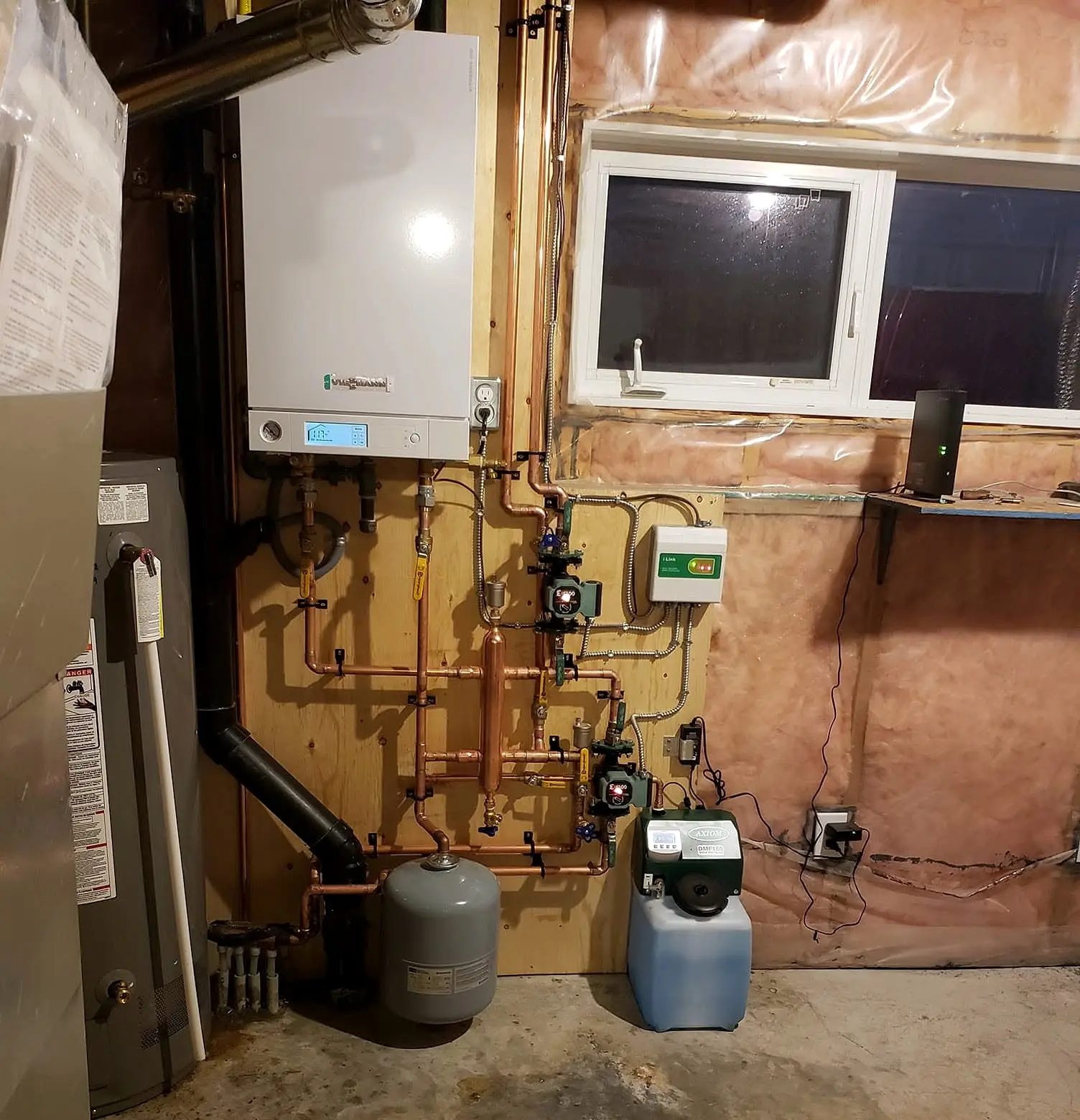Wall-mounted boiler with copper piping, circulators and expansion tank installed in a basement mechanical area