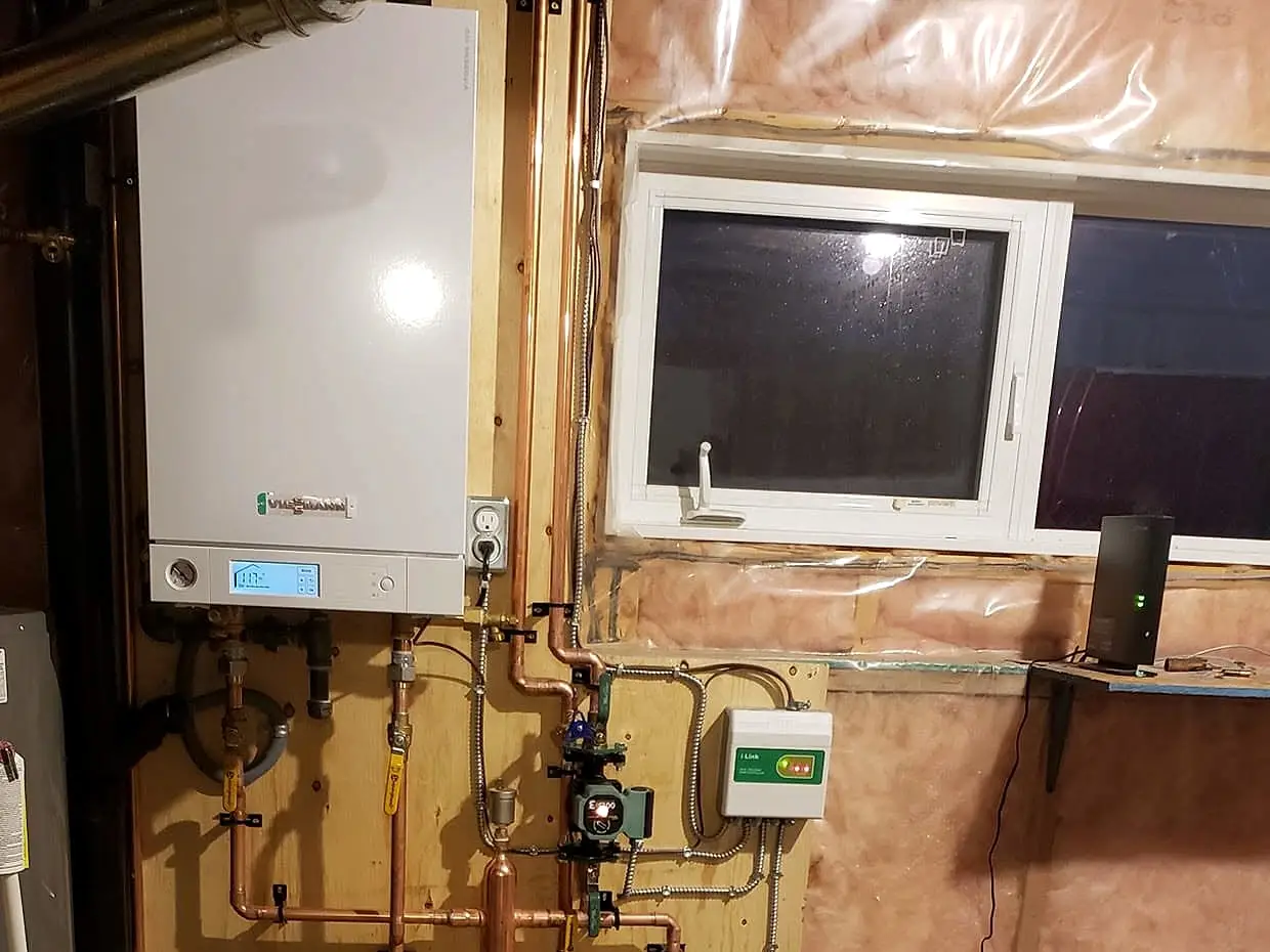 Wall-mounted boiler with copper piping, circulators and expansion tank installed in a basement mechanical area