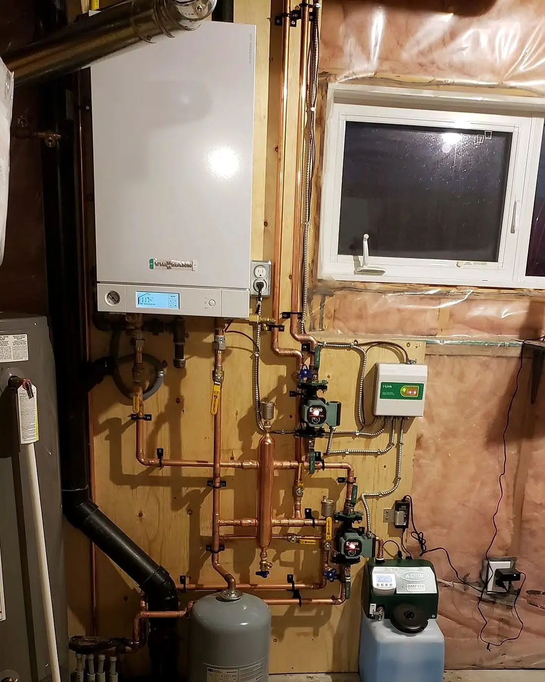 Wall-mounted boiler with copper piping, circulators and expansion tank installed in a basement mechanical area