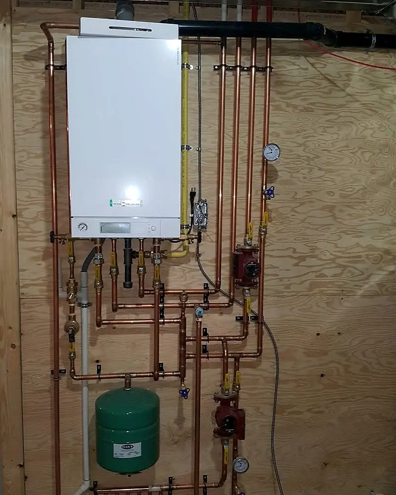 Wall-hung boiler with copper piping, circulator pumps and red in-floor heating loops feeding into a manifold