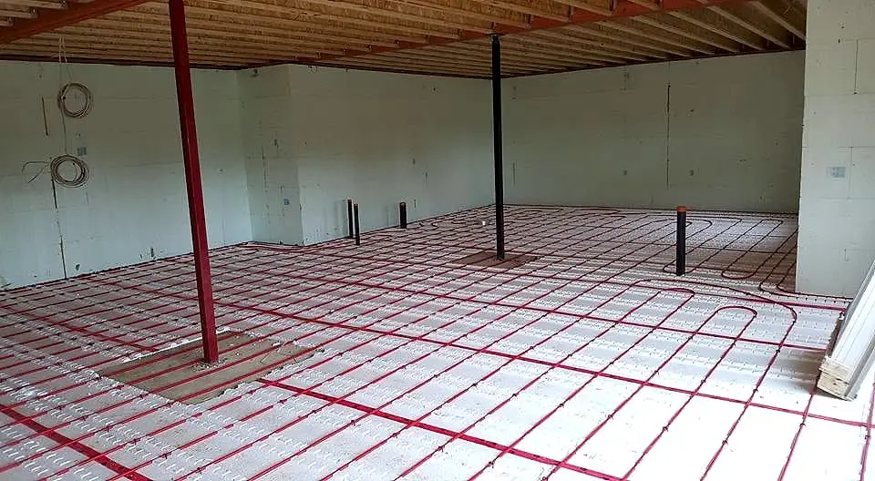 Red in-floor radiant heating tubing laid out in loops across insulated panels before the concrete pour