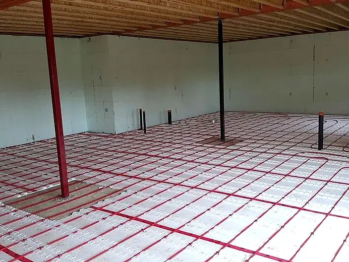 Red in-floor radiant heating tubing laid out in loops across insulated panels before the concrete pour